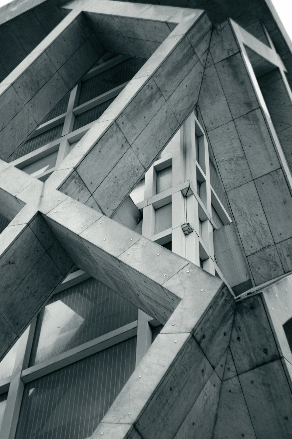 A low-angle photograph of a geometric concrete facade by Marc Cordeau.